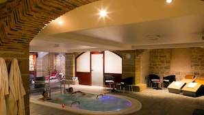 Un área de spa con jacuzzi, asientos y una pared de piedra.