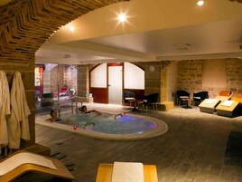 Un área de spa con jacuzzi, asientos y una pared de piedra.