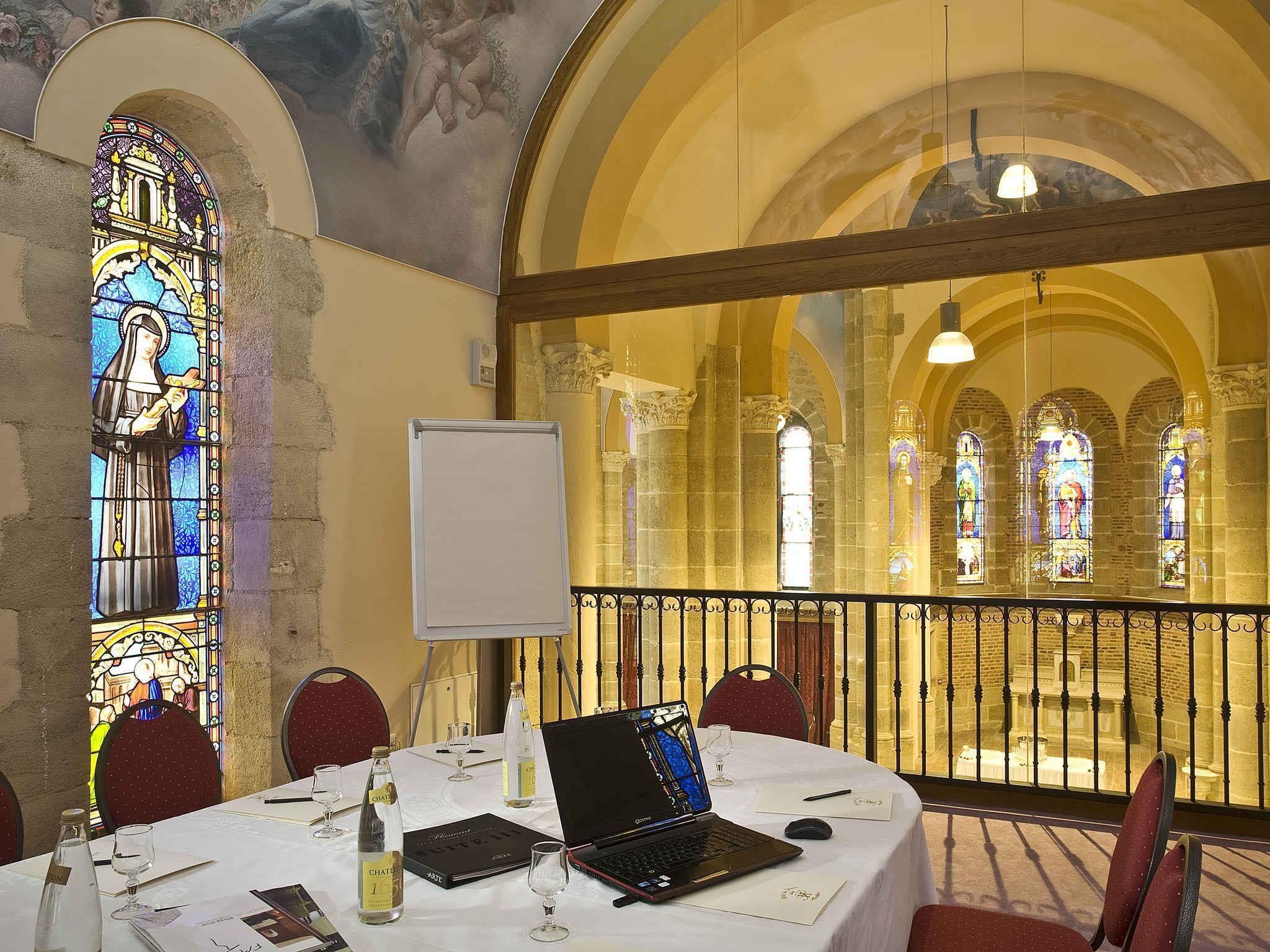 A conference room with a laptop, documents, and a bottle of Château Mouton Rothschild wine.