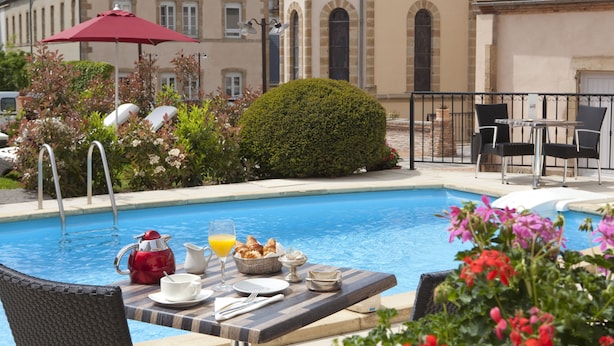 Desayuno junto a la piscina con una mesa, sillas y un paraguas rojo.