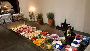 Un buffet proposant une variété de plats, notamment des viandes, des fruits de mer et des légumes, ainsi que des condiments et des boissons.