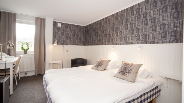 A hotel room with a large bed, a desk, and a chair. - Lages Motel & Restaurang (Bramhult)