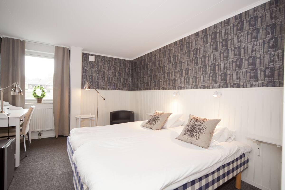 Quarto de hotel com uma cama grande, uma mesa e uma cadeira.