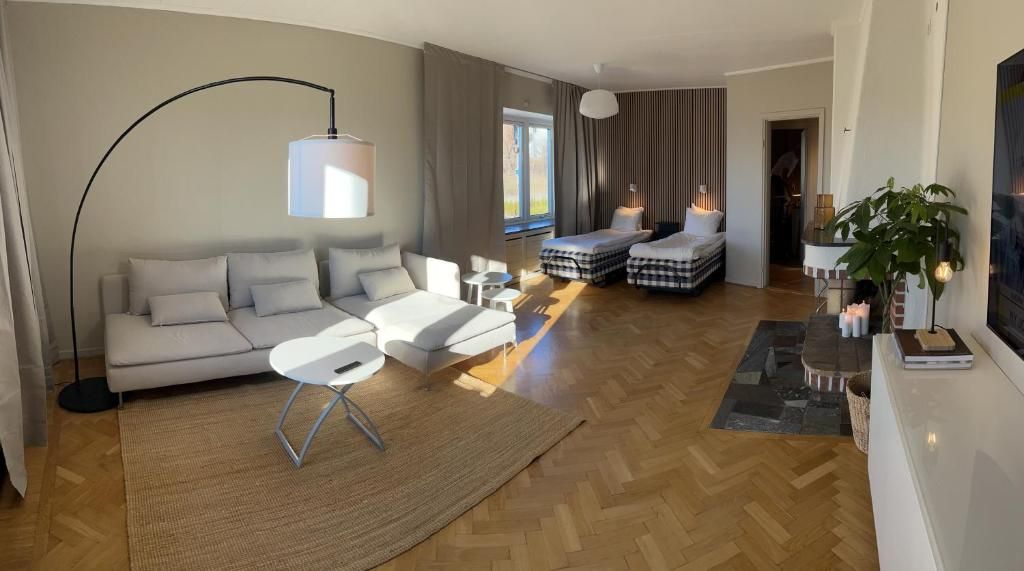 A modern living room with a sofa, two beds, a coffee table, and a large floor lamp.