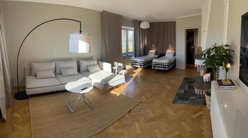 Una sala de estar moderna con un sofá, dos camas, una mesa de centro y una lámpara de pie grande.