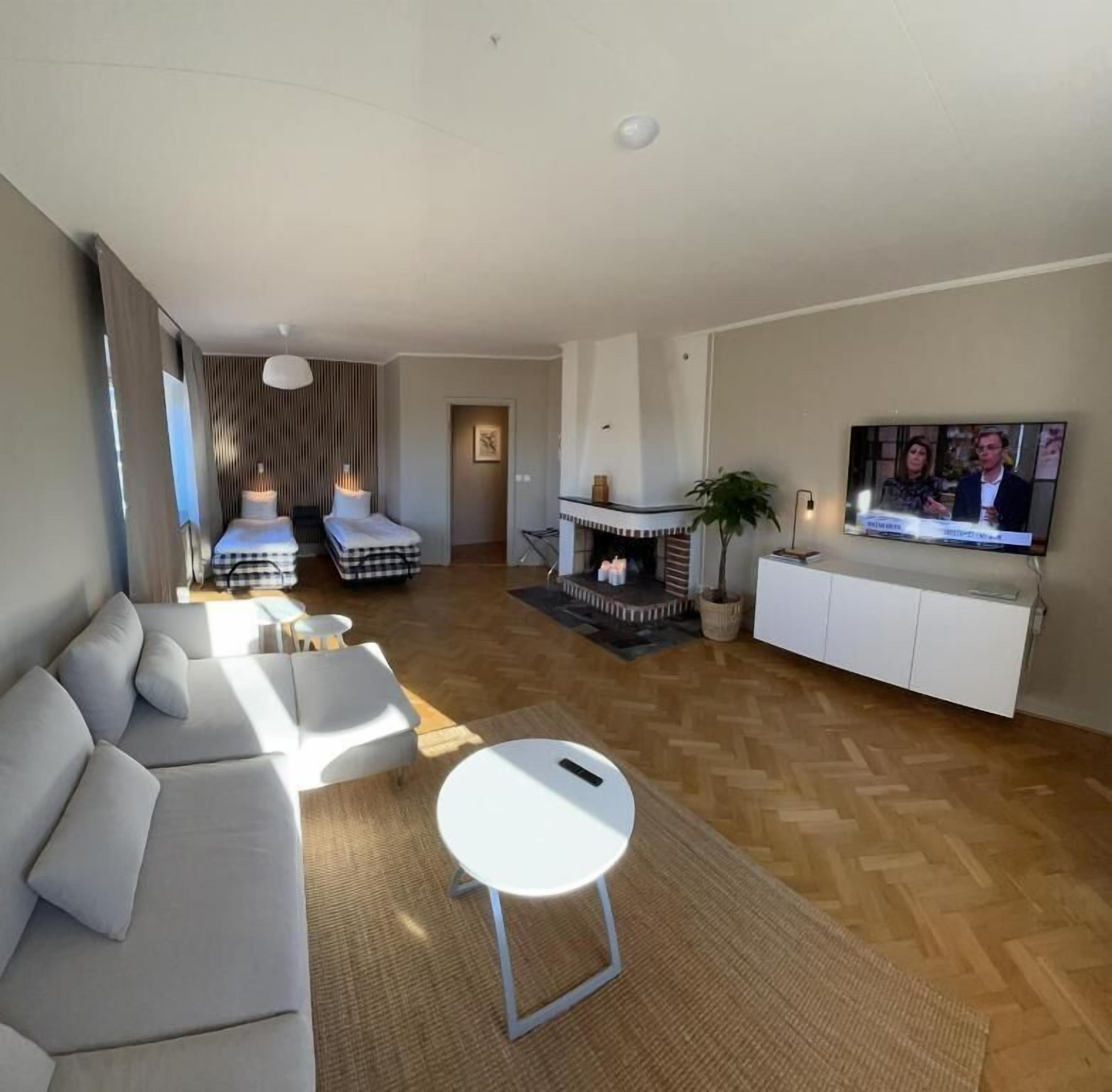 Una sala de estar moderna con un sofá, una mesita, un televisor y una chimenea.