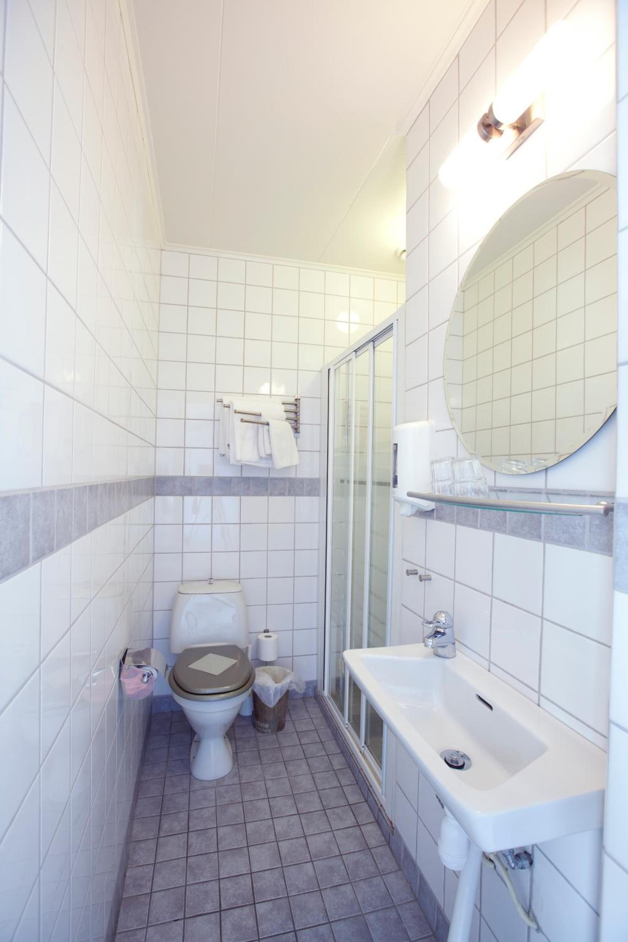 Un baño pequeño y limpio con inodoro, lavabo y cabina de ducha de vidrio.