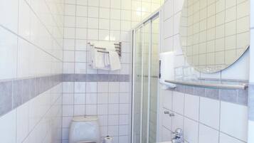 Un baño pequeño y limpio con inodoro, lavabo y cabina de ducha de vidrio.