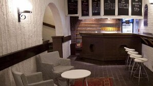 A bar area with a counter, stools, and a seating area with chairs and a table. - Lages Motel & Restaurang (Bramhult)