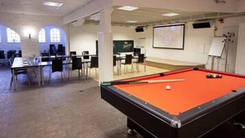 Una sala de billar con mesa de pool, sillas y pantalla de proyector.