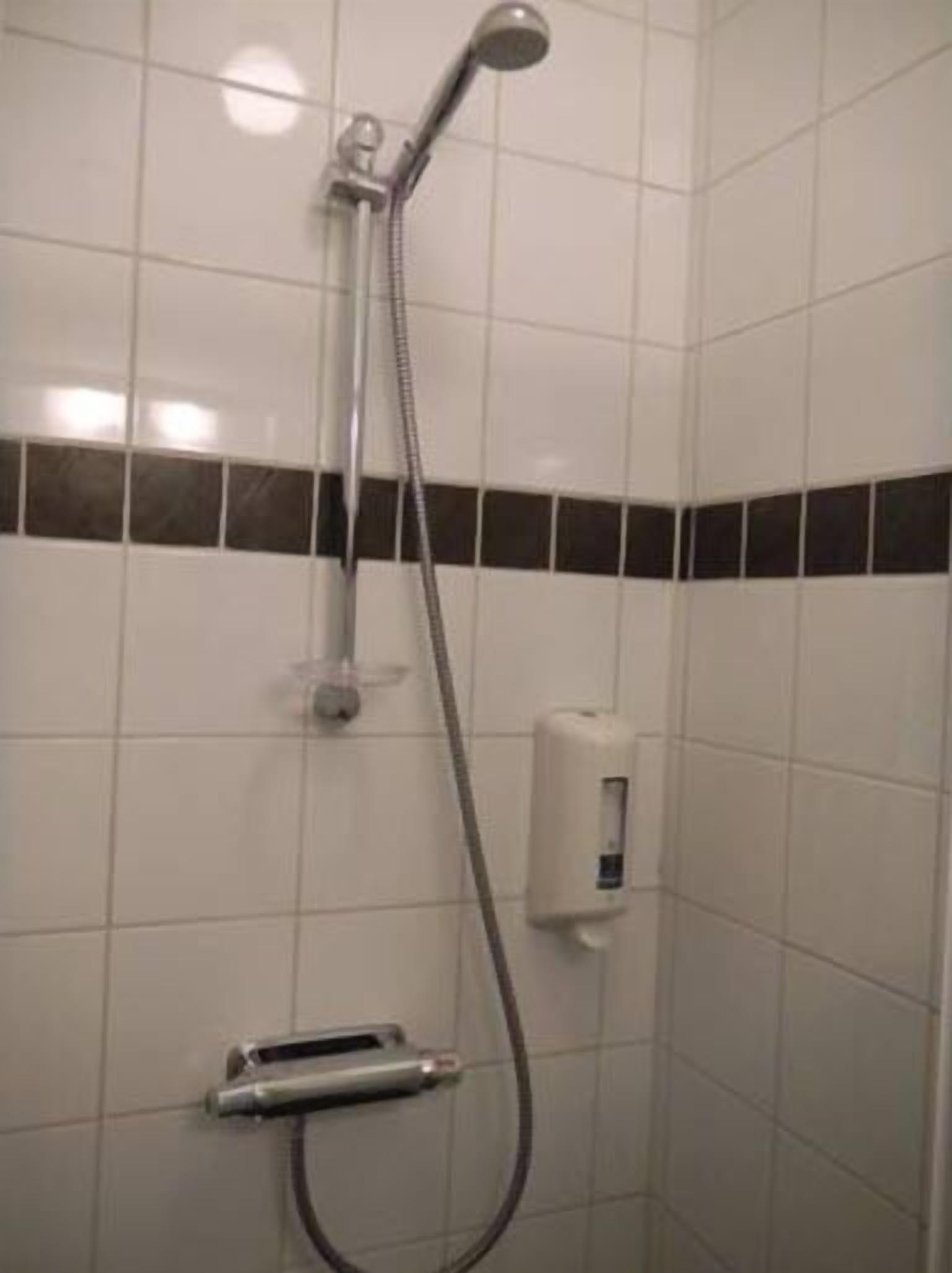 Una ducha con cabezal de ducha y manguera de mano.
