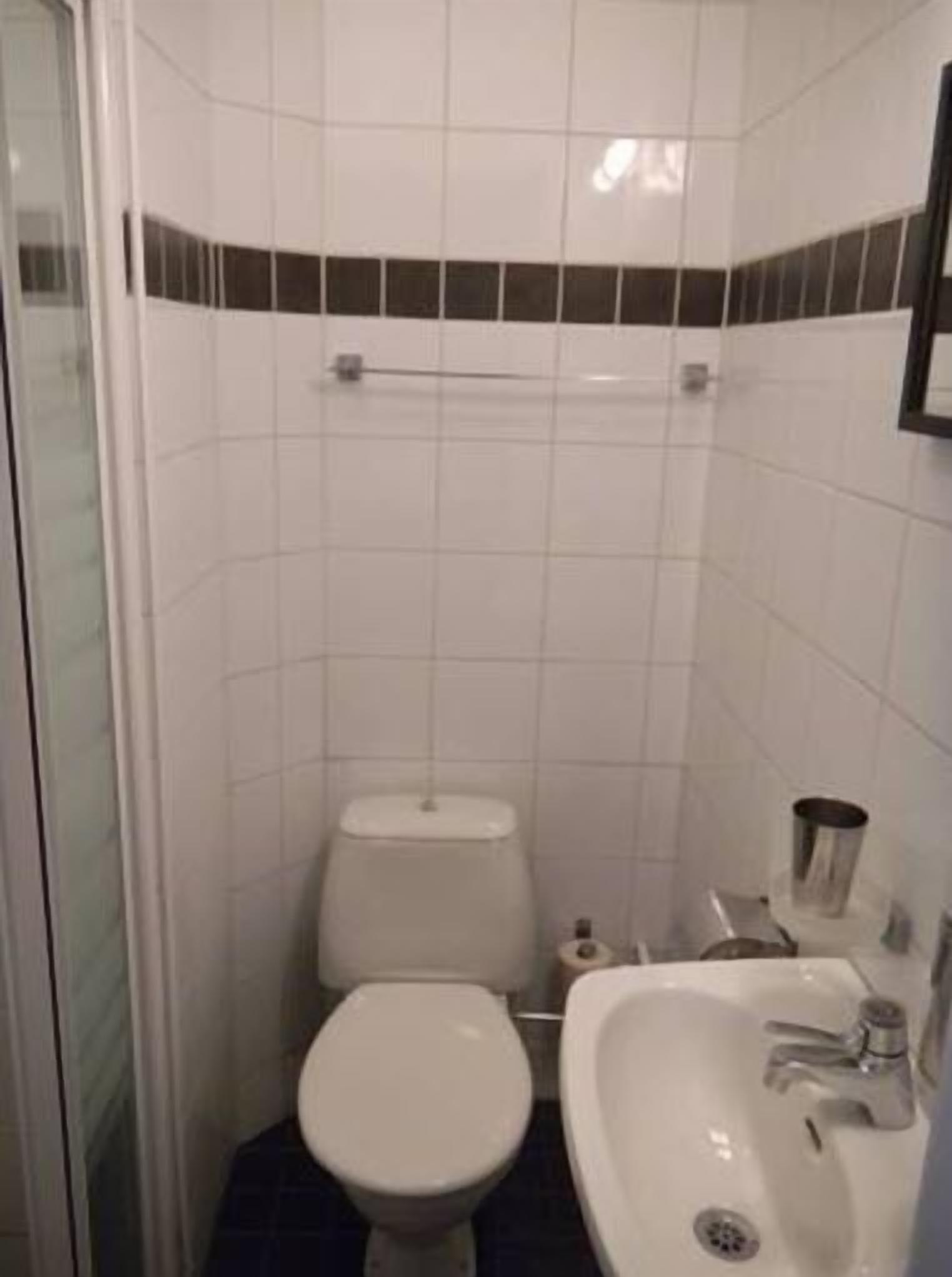 A small bathroom with a toilet, sink, and a towel rack.