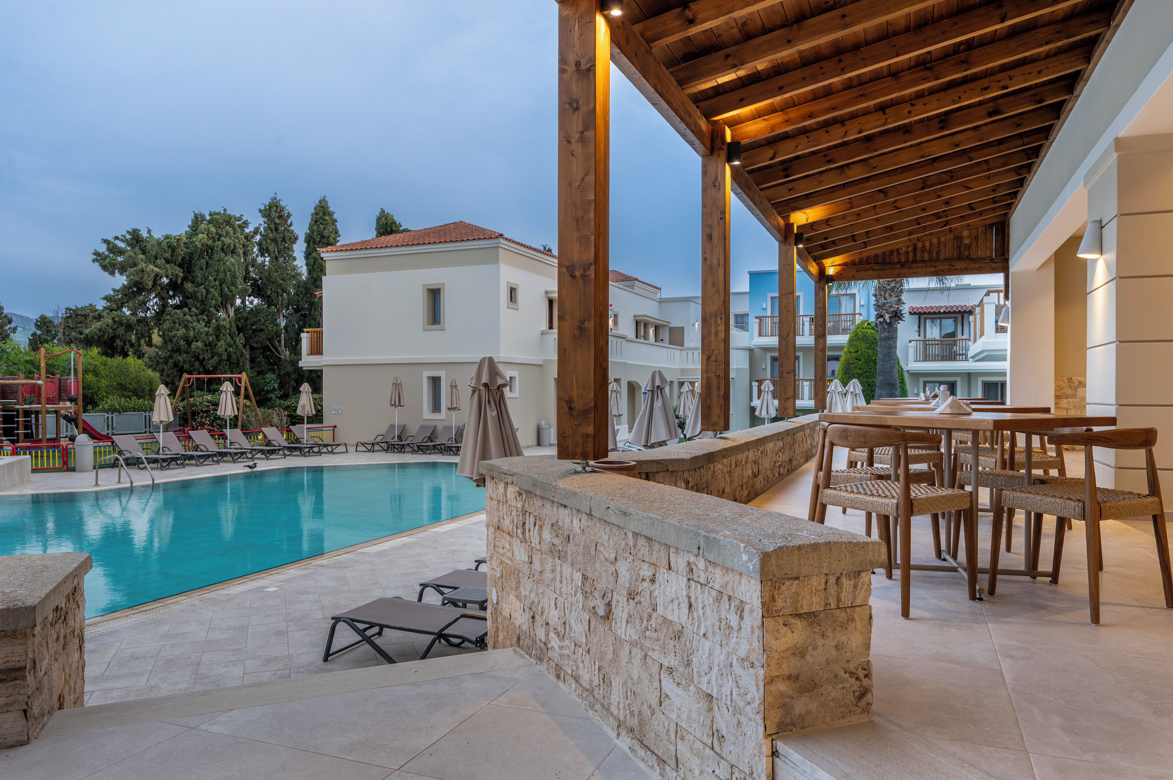 A poolside area with lounge chairs, a bar, and a covered seating area.