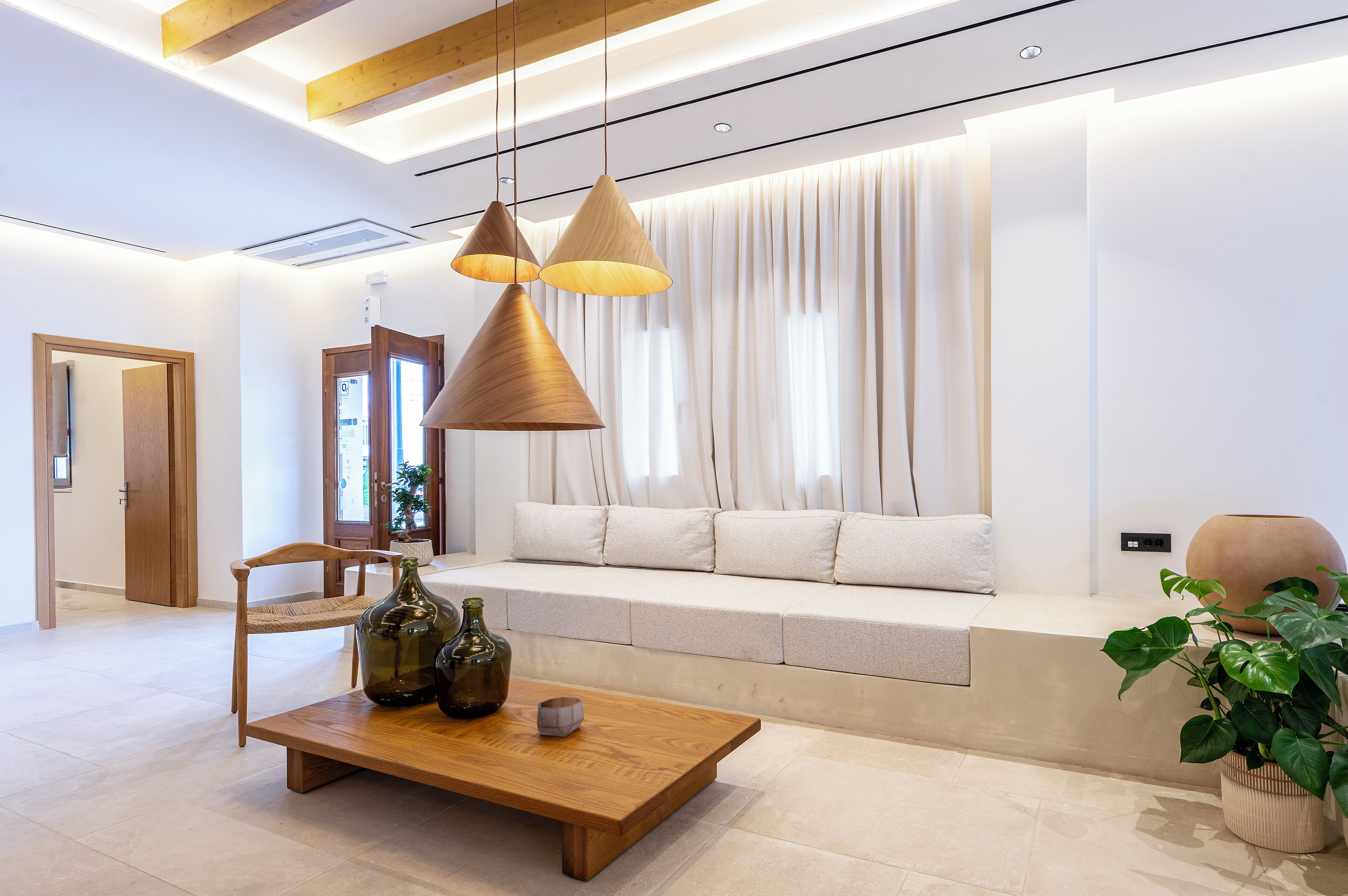 A modern living room with a wooden coffee table, a sofa with cushions, and pendant lighting.