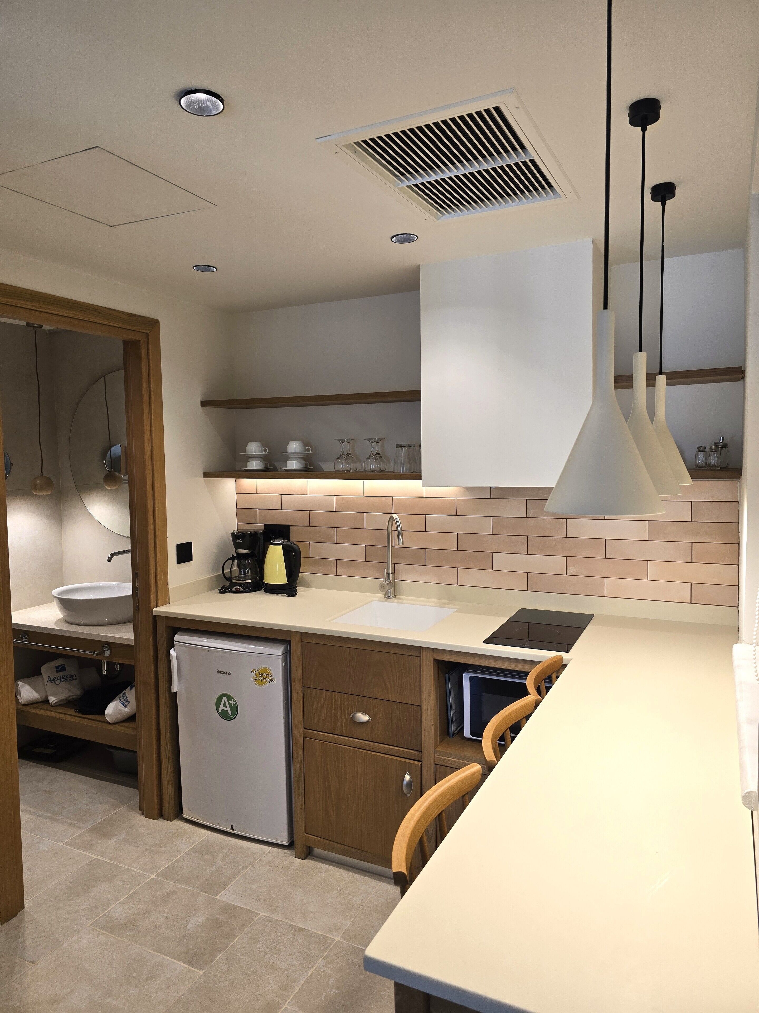 A modern kitchen with a white countertop, a sink, a coffee maker, and a refrigerator.