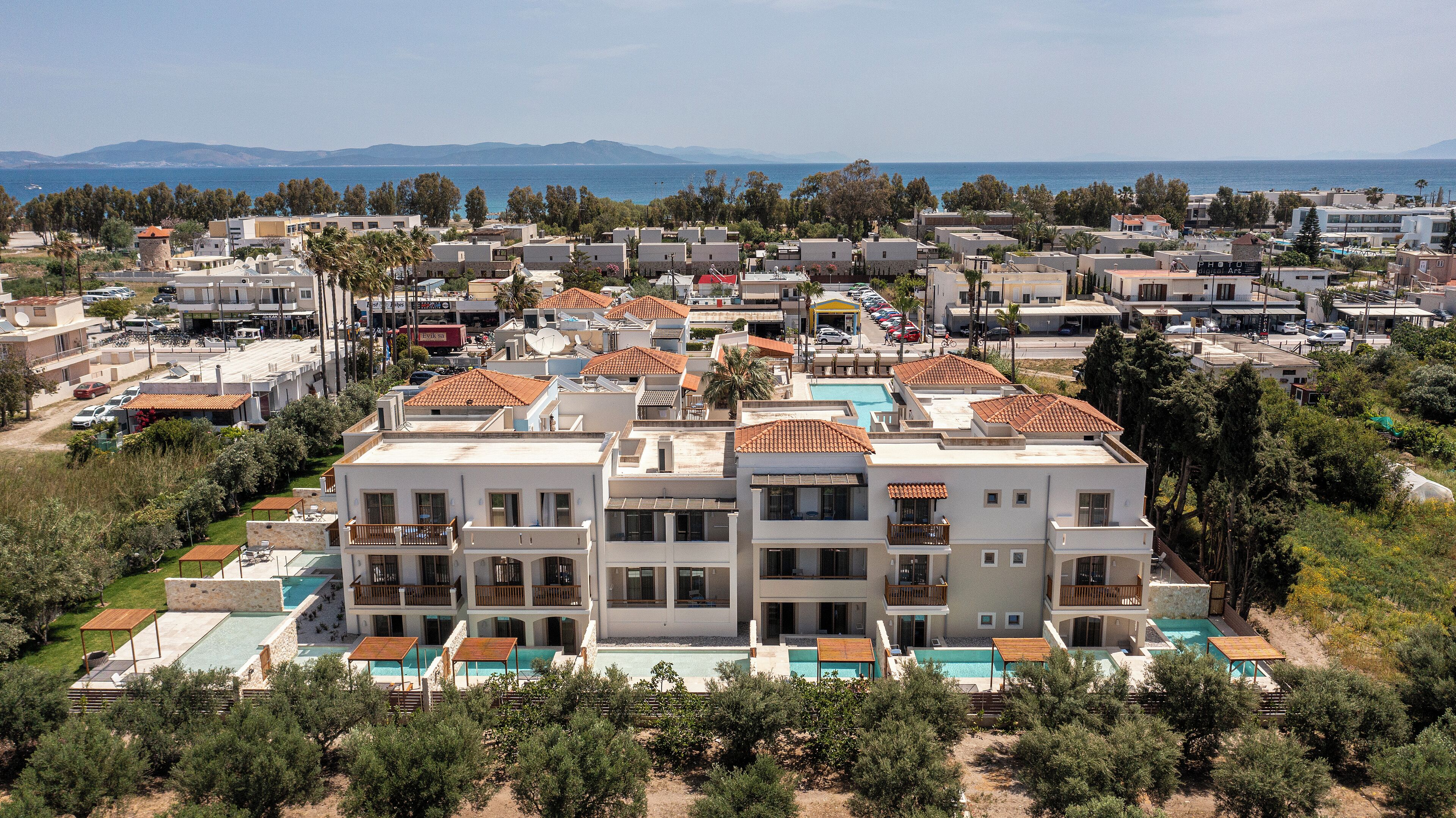 Zona residencial costera con varios edificios, una piscina y vista al mar.