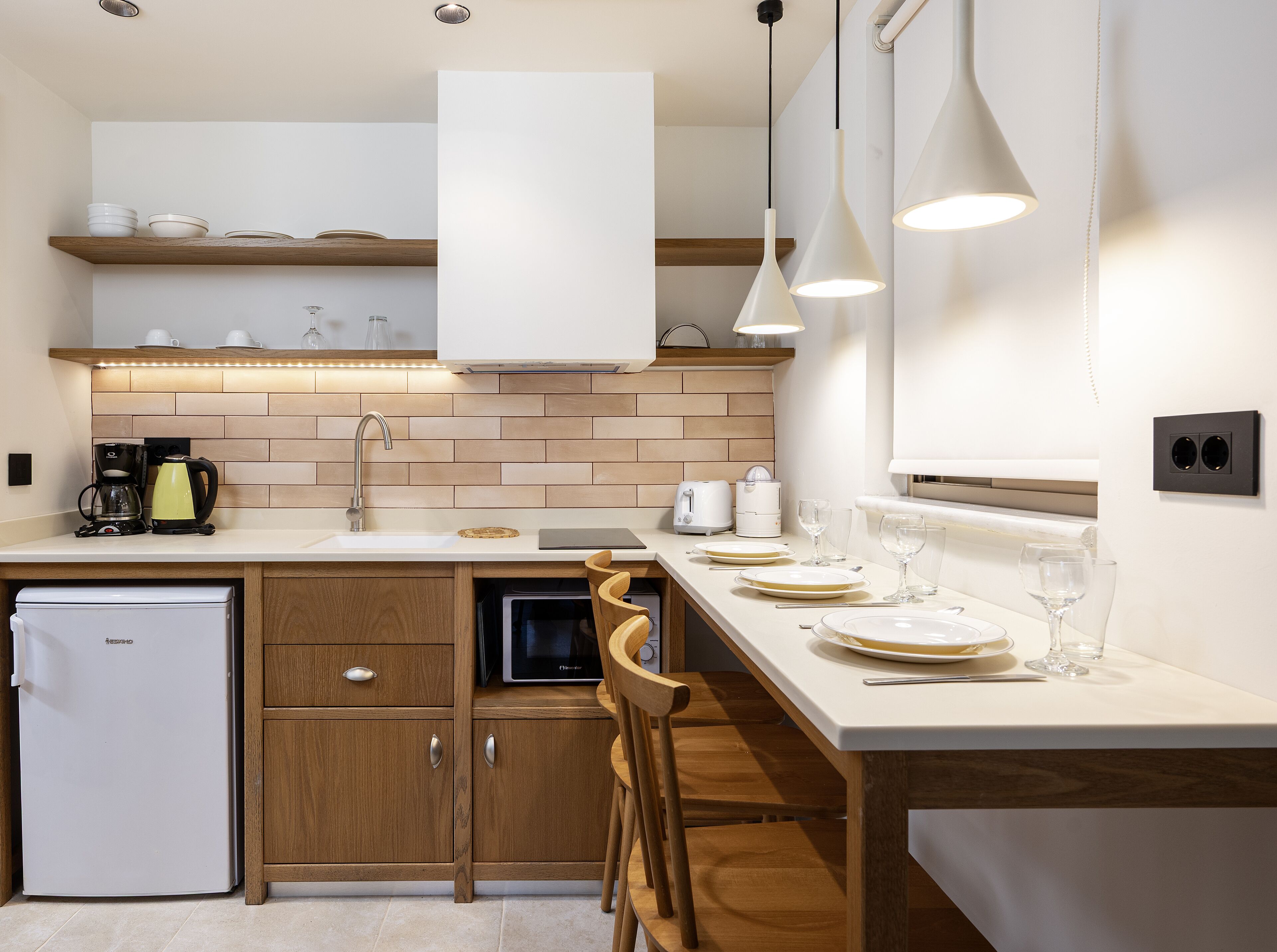 A modern kitchen with wooden cabinets, a built-in dishwasher, and a dining area with a table set for two.