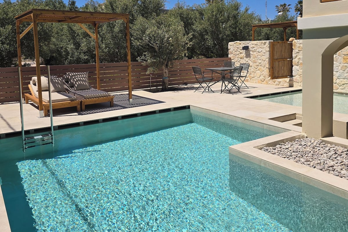 Piscina límpida com pergolado de madeira e espreguiçadeiras.