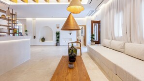 Un vestíbulo de hotel moderno con un mostrador de recepción de madera, un sofá y una mesa de centro con un jarrón.