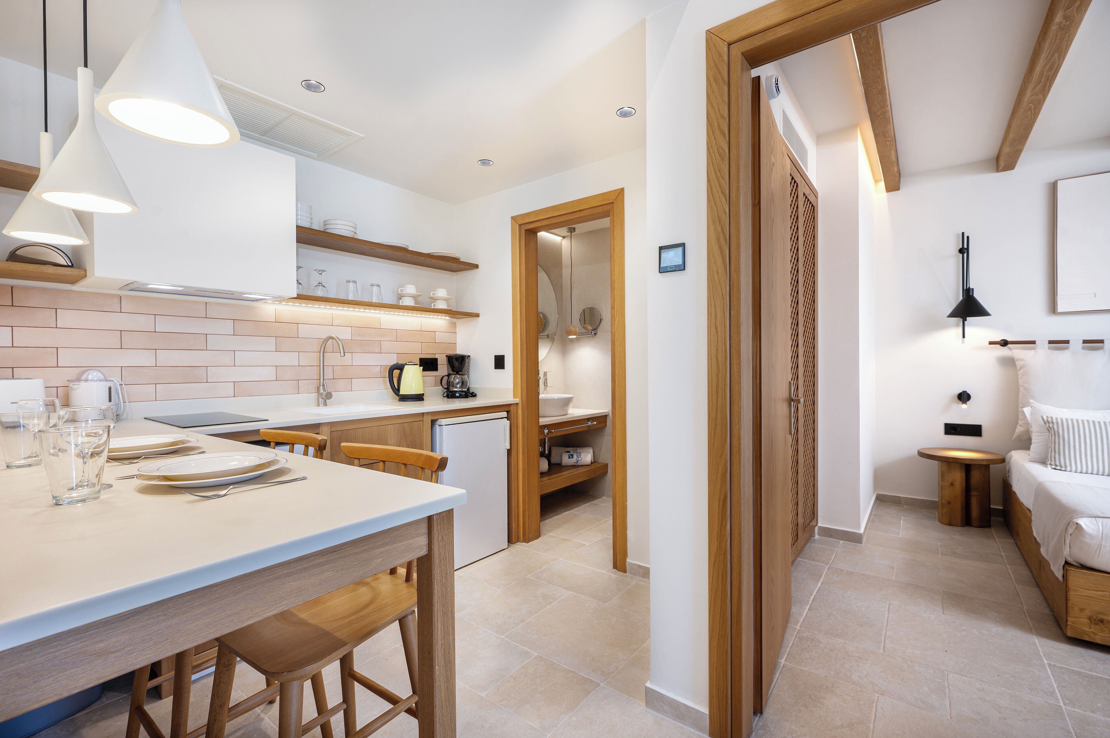 Una cocina moderna con una isla central, sillas de madera e iluminación colgante.