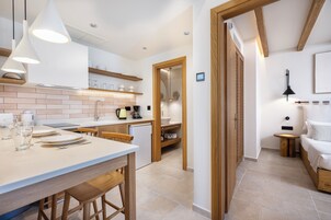 Una cocina moderna con una isla central, sillas de madera e iluminación colgante.