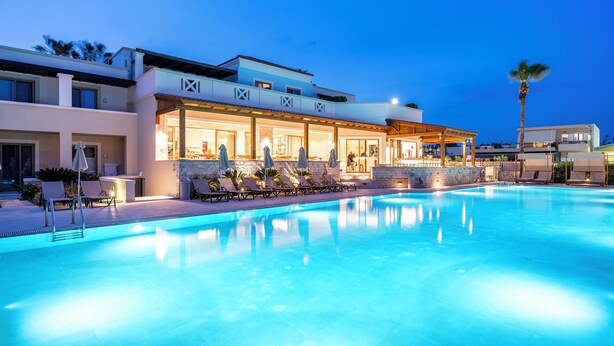 Un hotel moderno con piscina, tumbonas y un espacio al aire libre cubierto.