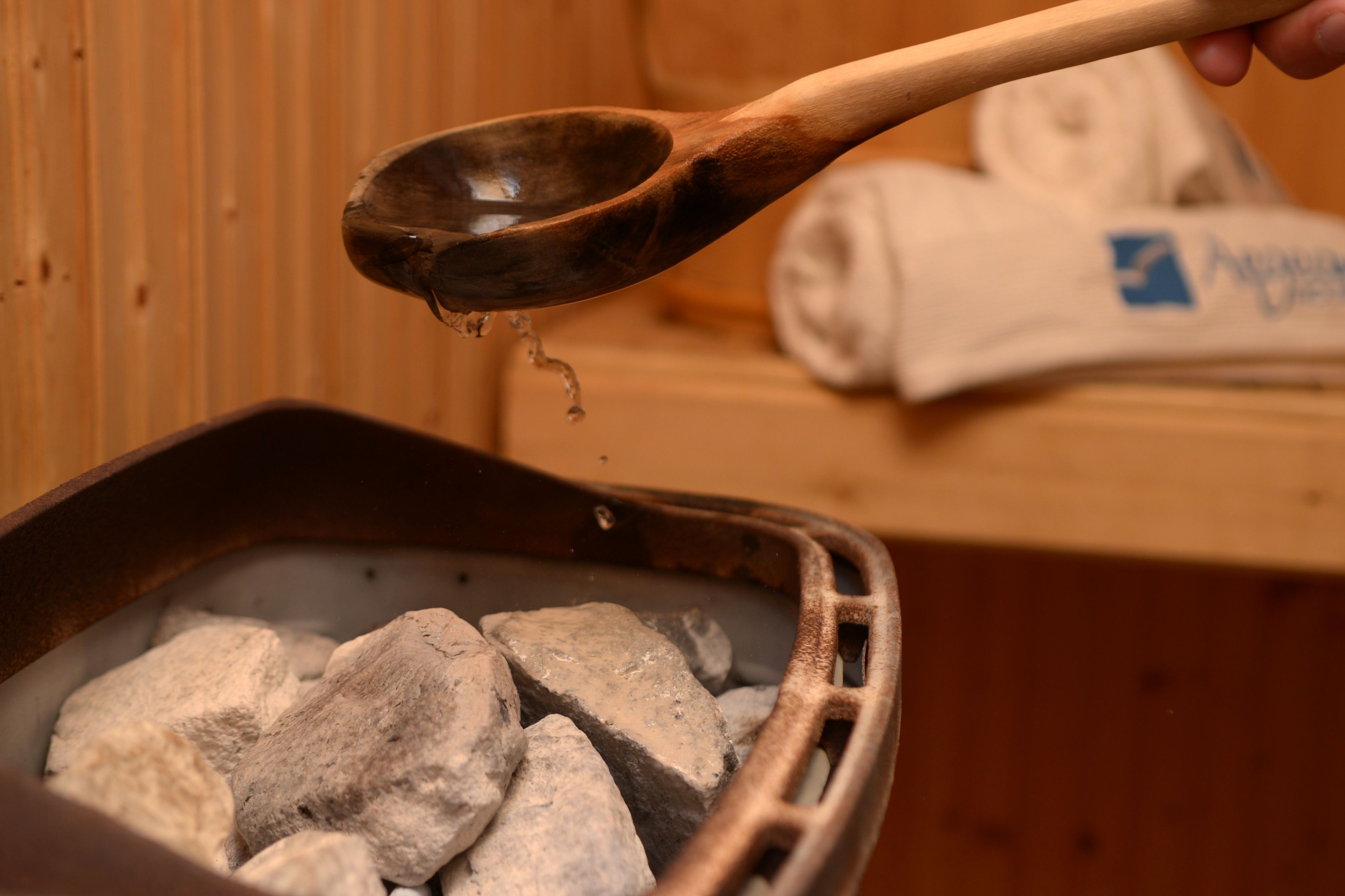 Una cuchara de madera levantando un líquido de una olla llena de carbón.