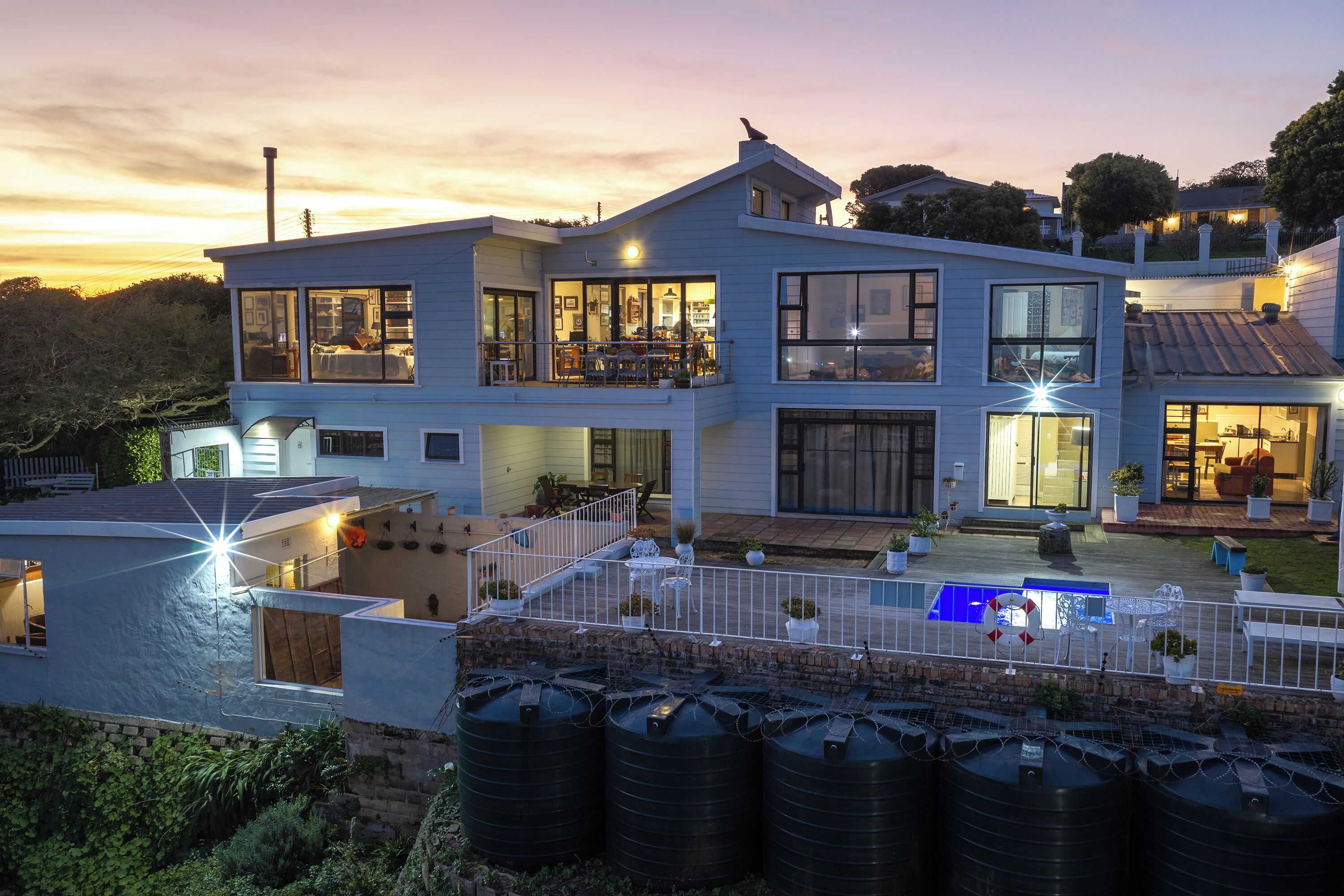 Una casa de dos pisos con ventanas amplias, un balcón y una piscina.