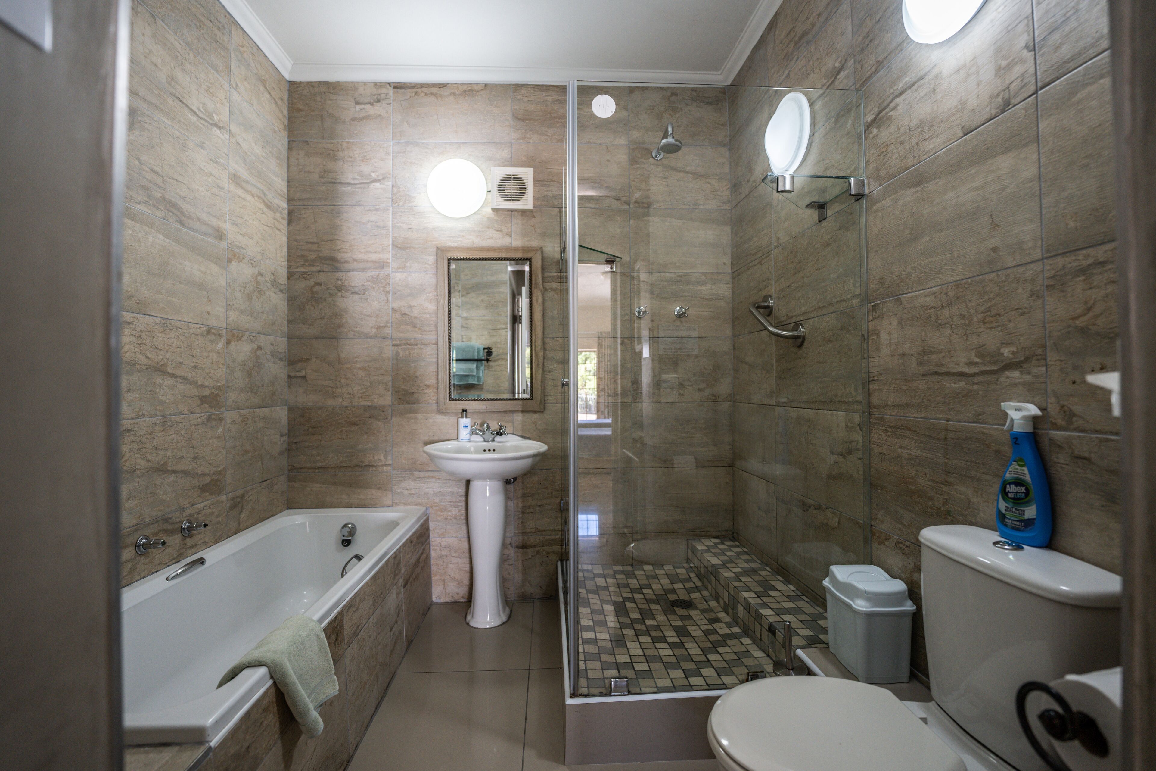 A modern bathroom with a bathtub, a sink, a toilet, and a shower area.