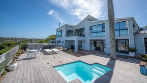A modern two-story house with a wooden deck, a swimming pool, and a view of the landscape. - The Lookout Guest House (Port Alfred)