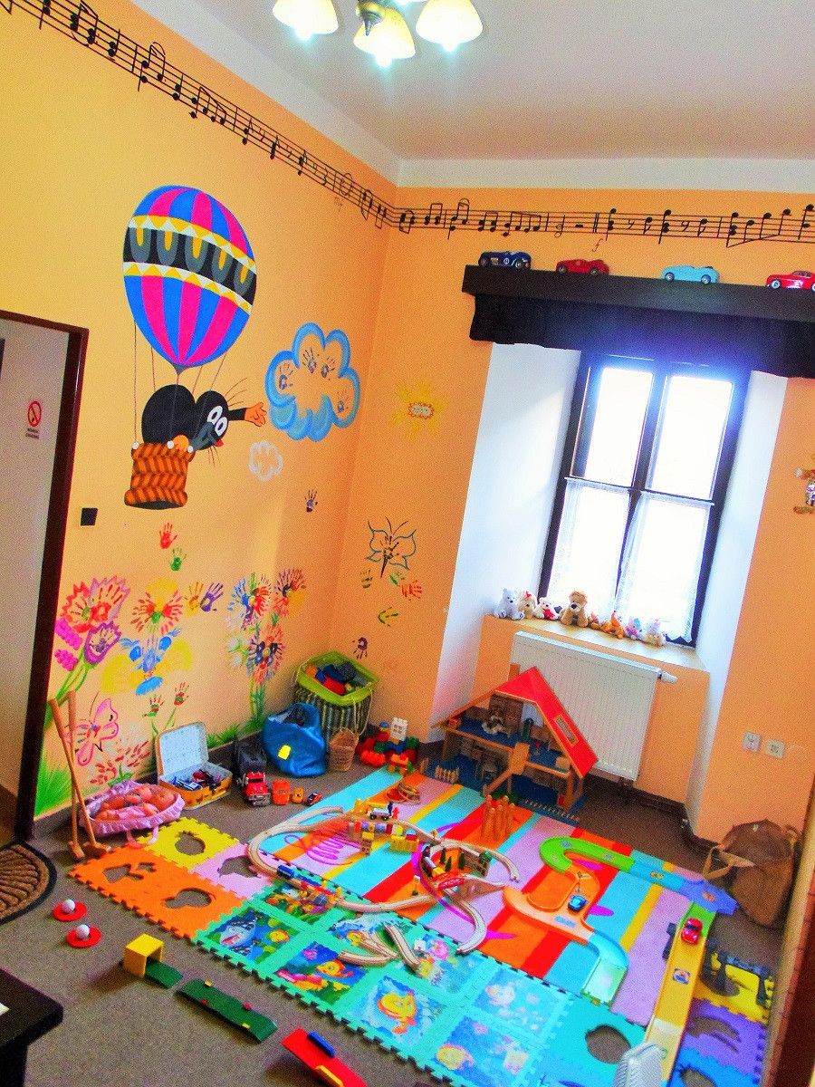 A child's playroom with a colorful play mat, toys, and wall decorations.
