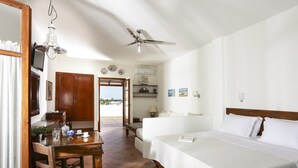 Habitación de hotel con cama, escritorio, silla, ventilador de techo y vistas al exterior.