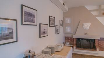A room with a fireplace, framed pictures on the wall, and a buffet table with plates and cups.