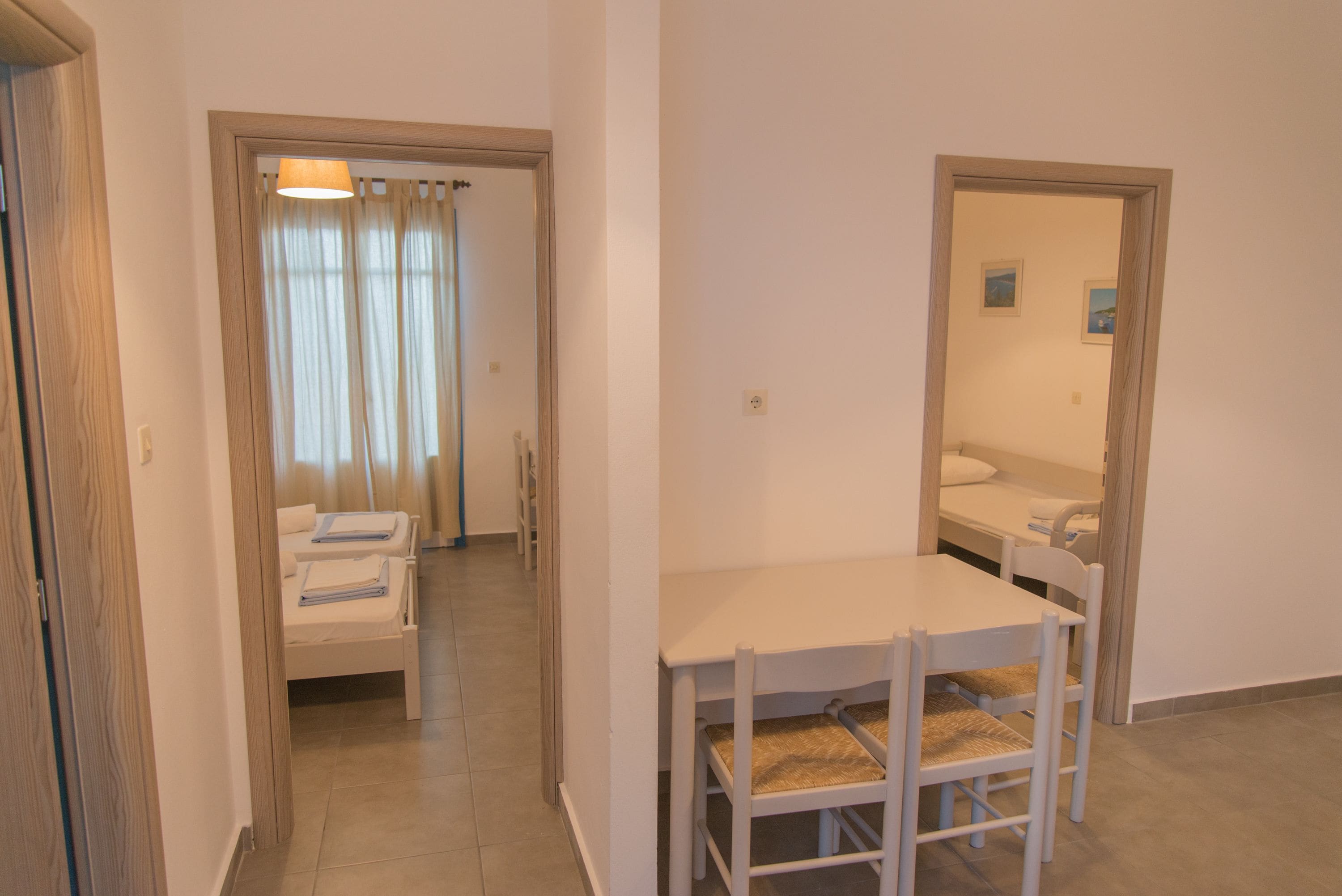 Habitación de hotel con cama, una mesita con sillas y baño visible a través de una puerta abierta.