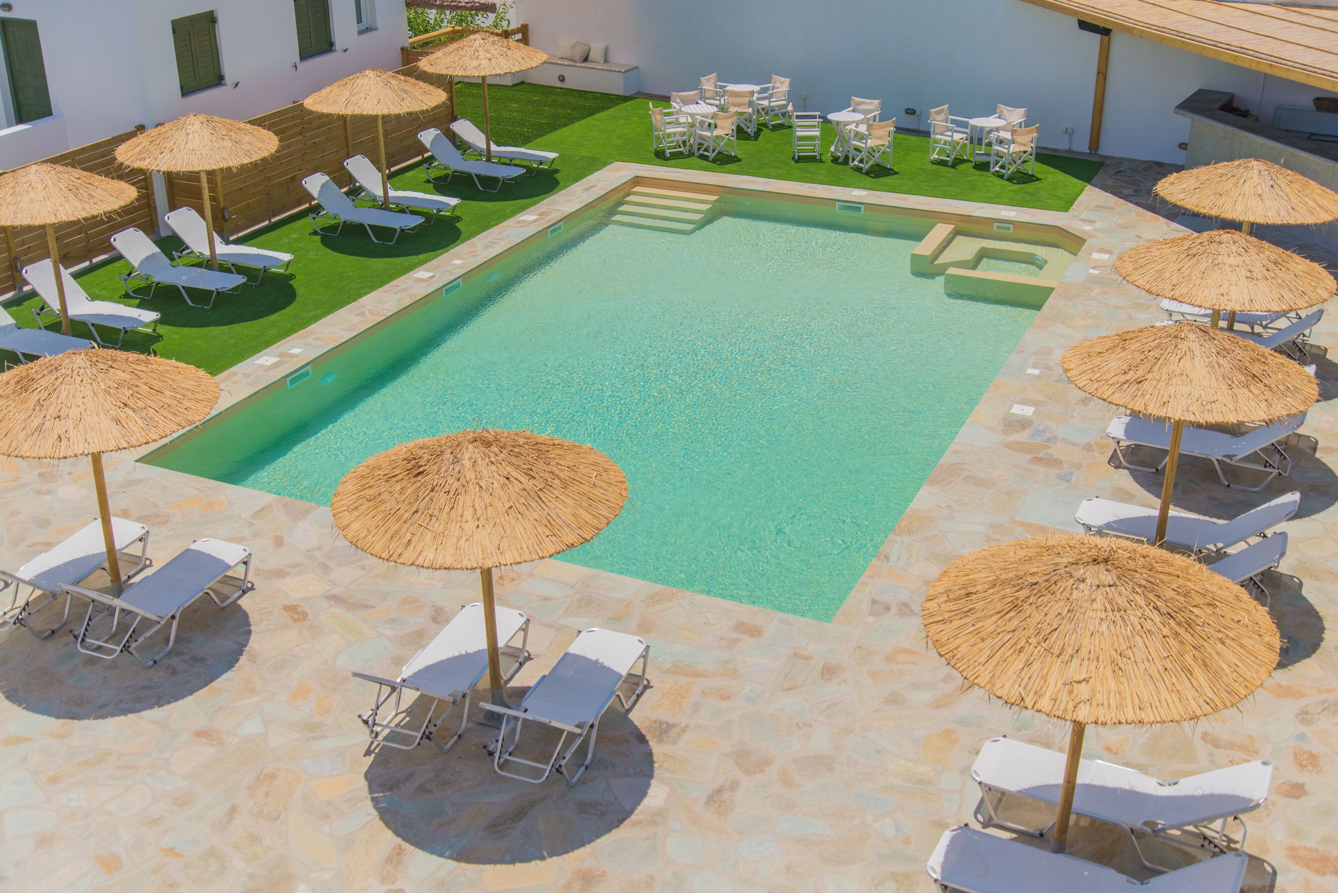 A swimming pool with sun loungers and umbrellas, surrounded by a stone deck.