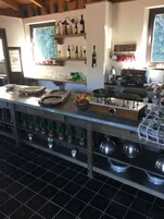Una cocina con una encimera larga, diferentes utensilios de cocina y una cafetera.
