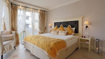 A hotel room with a large bed, a chair, a nightstand with a lamp, and a view of the outside.