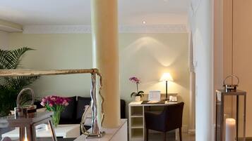 Un moderno vestíbulo de hotel con una recepción, una zona de estar y una columna decorativa.