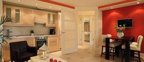 Una cocina moderna con armarios de madera, un área de comedor con una mesa y sillas, y una pared de acento roja.