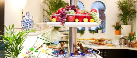 A multi-tiered fruit and cereal display with various bowls of cereal and a decorative plant on top.