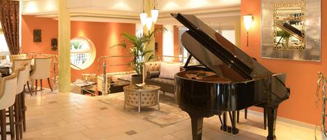 A grand piano in a well-lit living room with a round table, chairs, and a sofa.