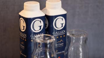Two Gallen Hospitality branded bottles and two coasters with the hotel's logo.