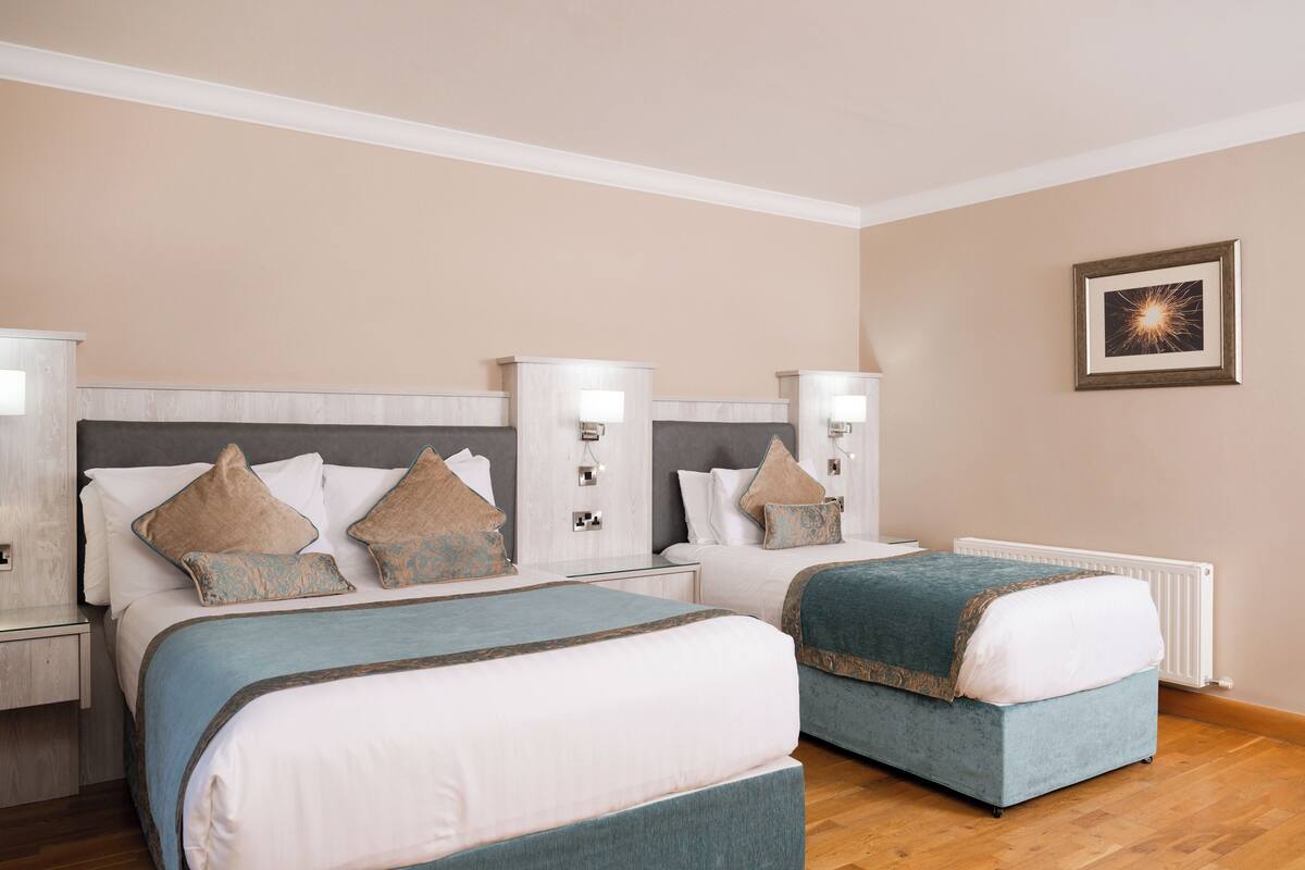 A hotel room with two beds, a nightstand, a dresser, and a framed picture on the wall.