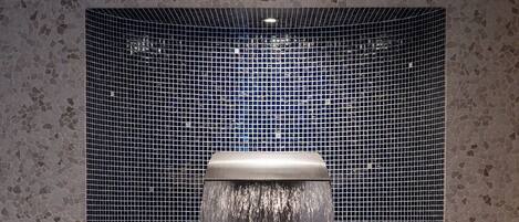 Un jacuzzi con pared de azulejos y barandilla de metal.