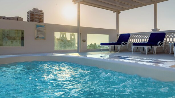 An indoor swimming pool with blue chairs and a pergola. - Hotel Coral Reef Cartagena (Cartagena)
