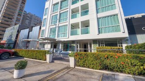 A modern hotel with multiple floors, large windows, and a covered entrance area with outdoor seating. - Hotel Coral Reef Cartagena (Cartagena)