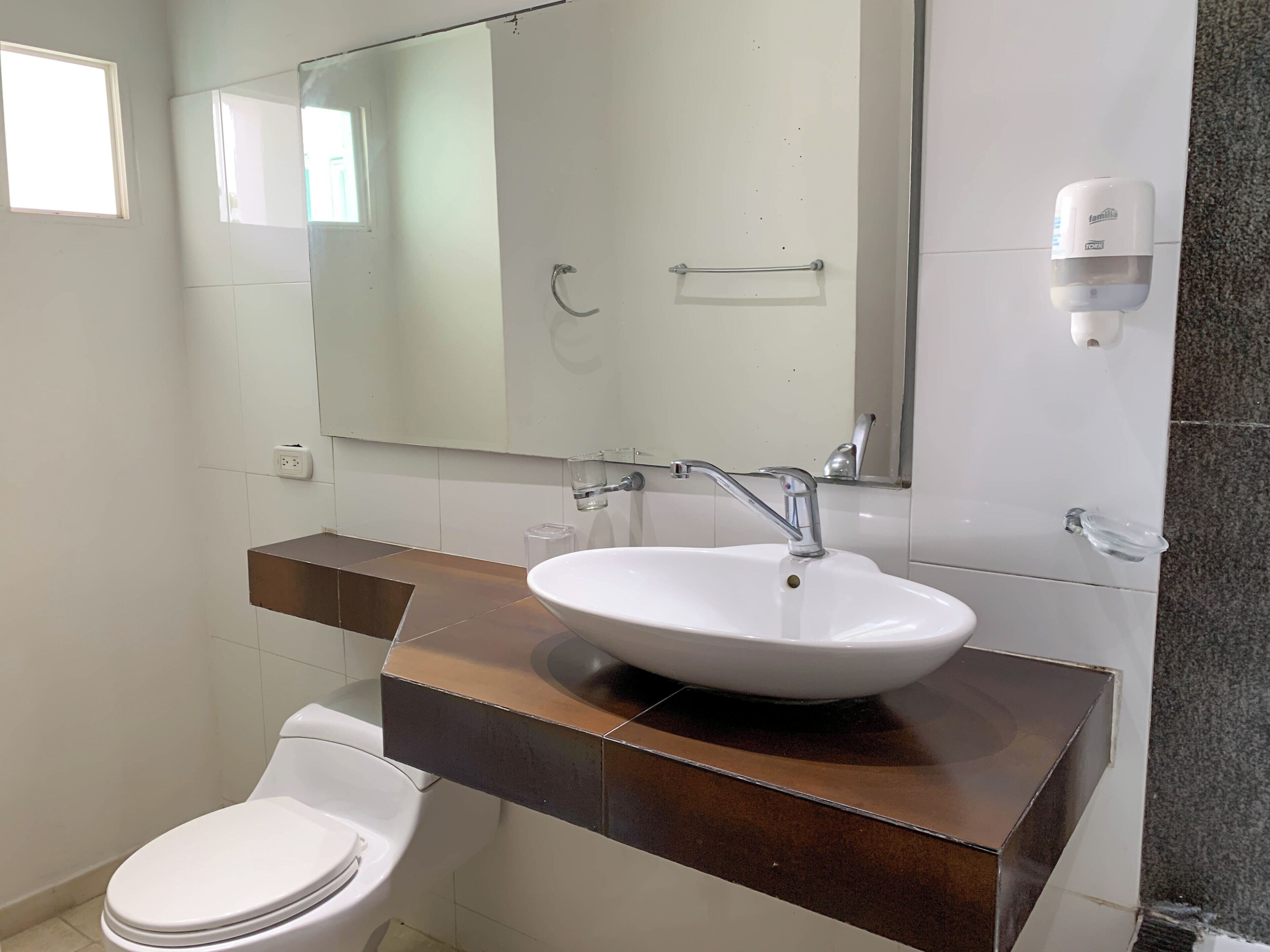 Une salle de bain avec un lavabo blanc, un miroir et des toilettes.