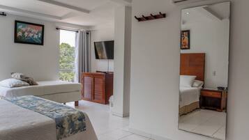 A hotel room with a bed, a bedside table, a TV, a wardrobe, and a large mirror.