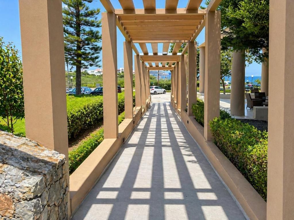 A covered walkway with a stone wall on one side and a row of trees on the other.