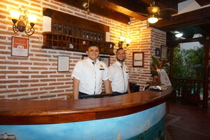Una recepción con pared de ladrillo, certificados enmarcados y mostrador de madera.